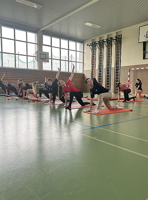 Schülerinnen turnen auf Yogamatten