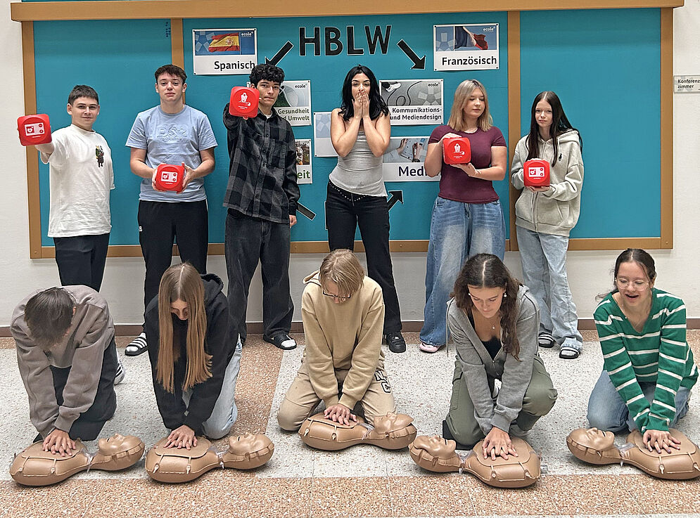 Schülergruppenbild vor der ecole-Wand mit Reanimationspuppen