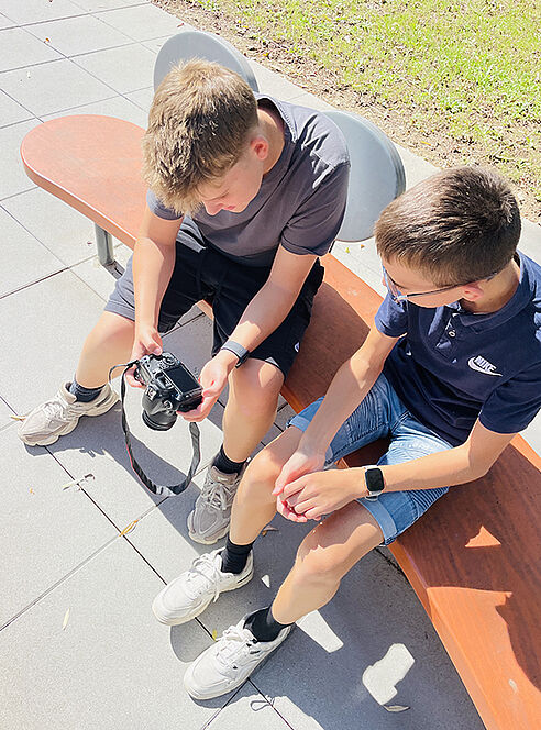 Zwei Schüler sehen sich eine Kompaktkamera an