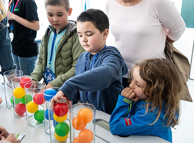 Schüler vor Gläsern mit bunten Bällen