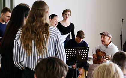Chor steht um Lehrer mit Gitarre und singen