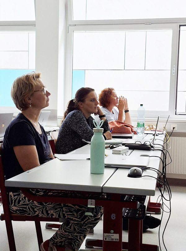 Lehrerinnen in der Bankreihe hören aufmerksam zu