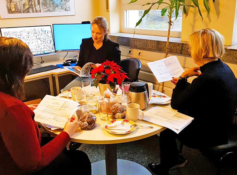 Drei Frauen am runden Kaffeehaustisch lesen im Programm