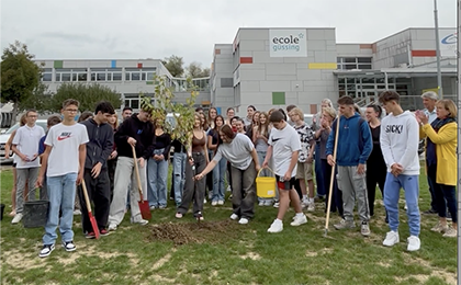 Schüler vor Schule pflanzen Bäume