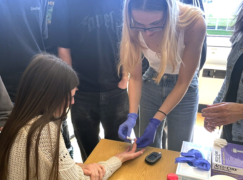 Schülerin nimmt Blut bei Finger ab