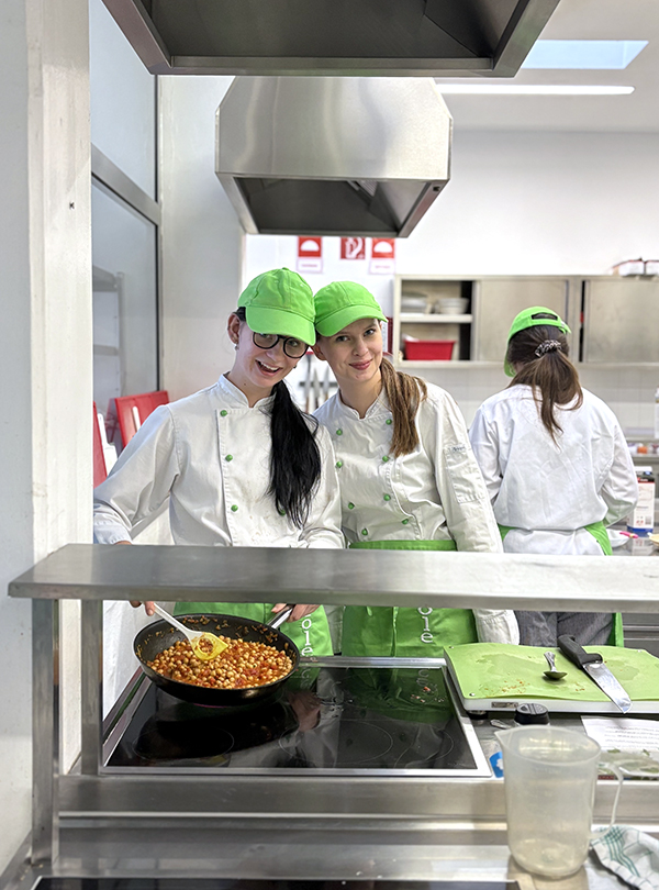 zwei Schülerinnen in Kochkleidung in der Küche