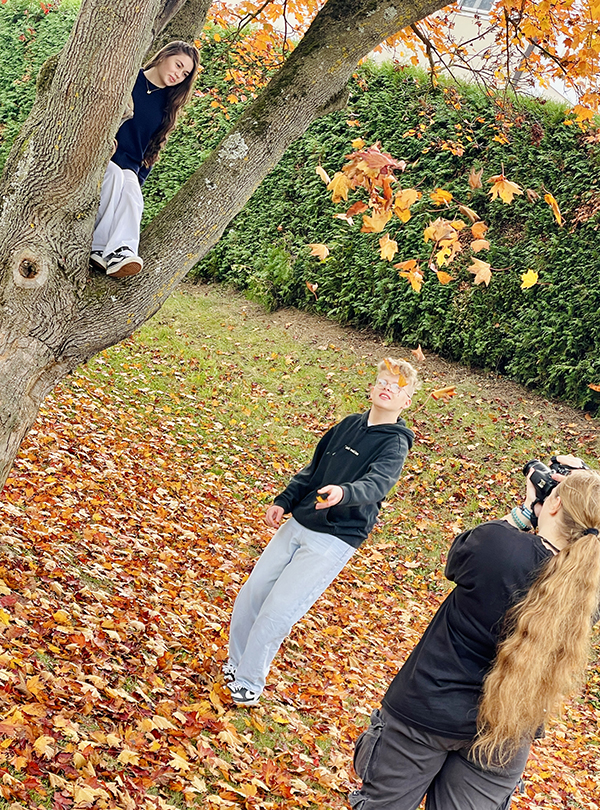 drei Schüler beim Fotografieren im Herbstlaub