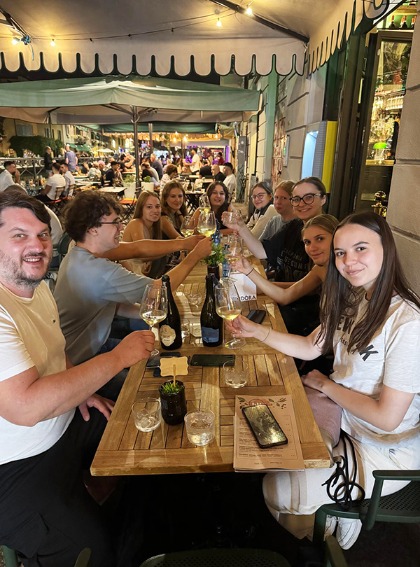Prosten mit Glas Wein am Abend vor einem Lokal