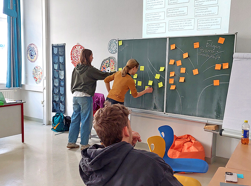 Schülerinnen kleben PostIts auf die Tafel