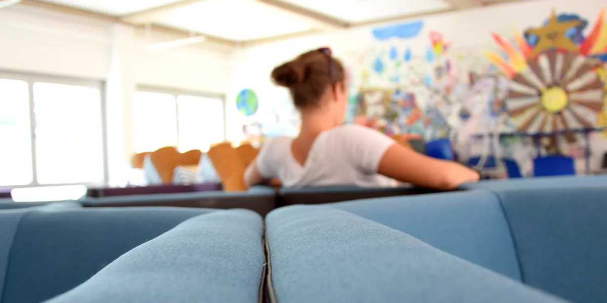 Schülerin in der Aula der ecole güssing vor der bemalten Wand