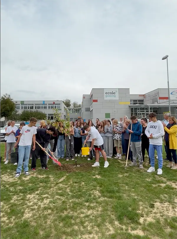 Schüler vor Schule pflanzen Bäume